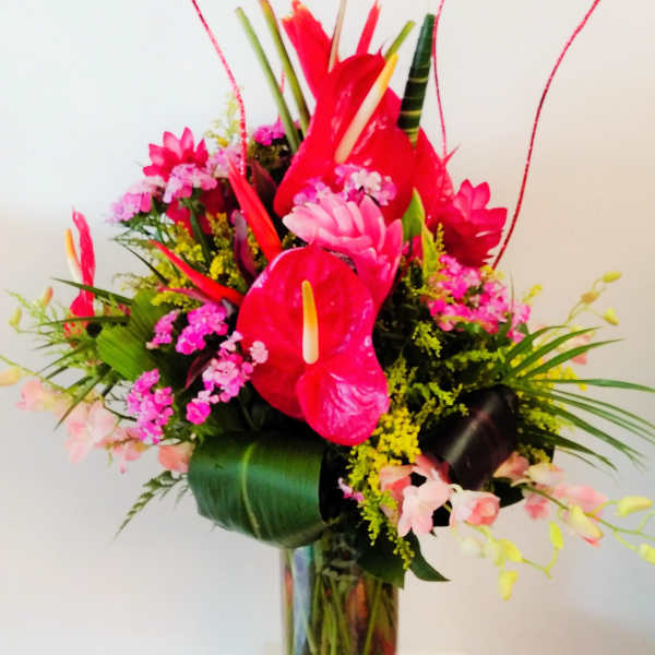 Bright tropical bouquet with red anthuriums in a glass vase