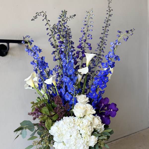Tall blue and white floral arrangement in a glass vase