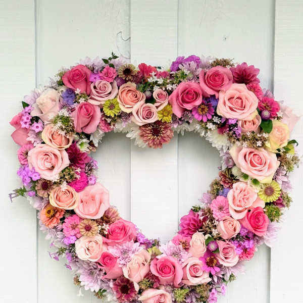 Heart-shaped floral wreath with pink roses and mixed blooms