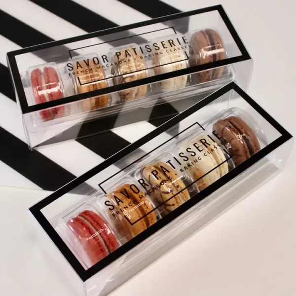 Two clear boxes of assorted macarons with black trim