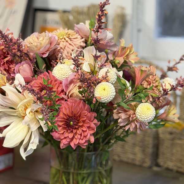 Mixed pink and cream flowers arranged in a clear glass vase
