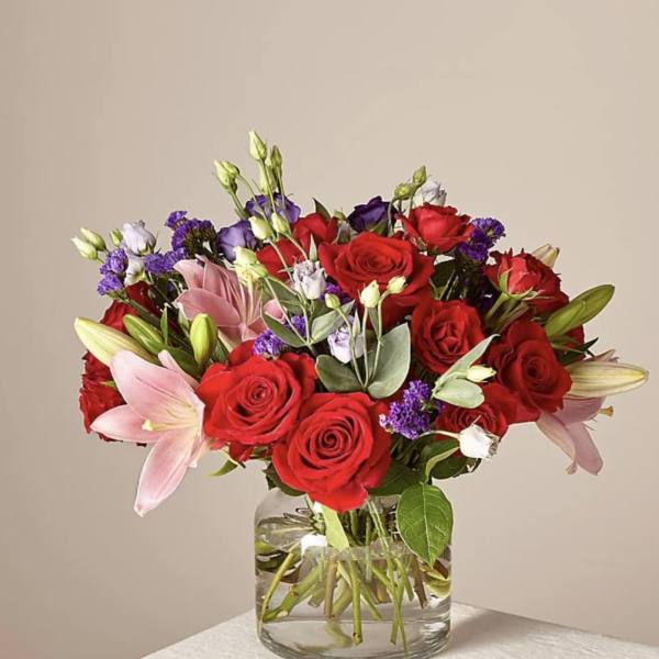 Bouquet of red roses and pink lilies in a clear glass vase