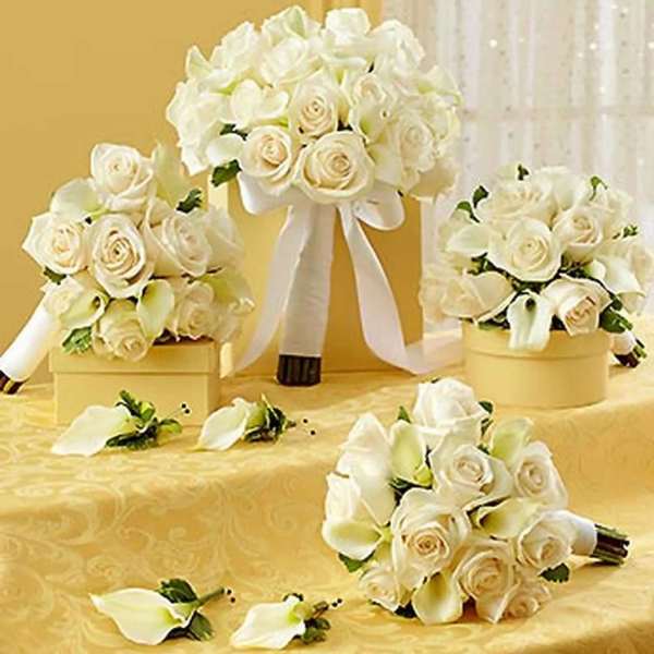 White rose and calla lily bouquets with ribbon on a gold table