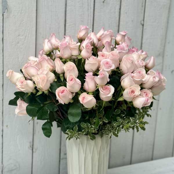 Bouquet of pale pink roses in a tall white vase