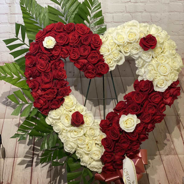 Heart-shaped arrangement of red and white roses with palm leaves