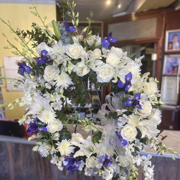 White floral wreath with blue accents and a sheer ribbon