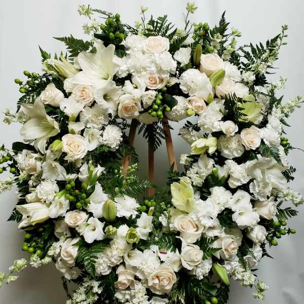 Large white floral wreath on a wooden stand