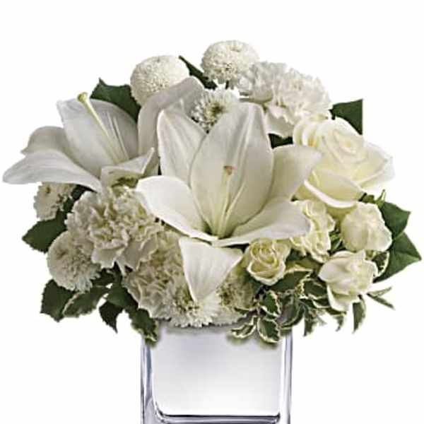 White floral arrangement in a clear square vase