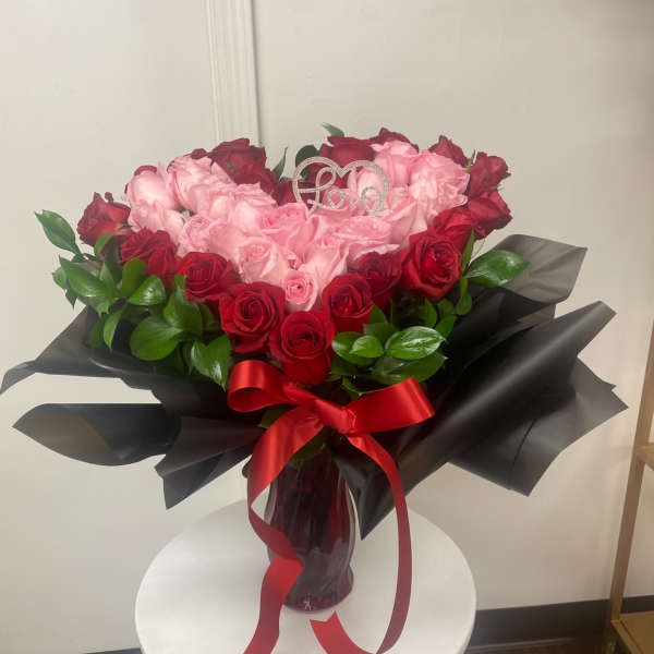 Bouquet of pink and red roses in a glass vase with a red ribbon