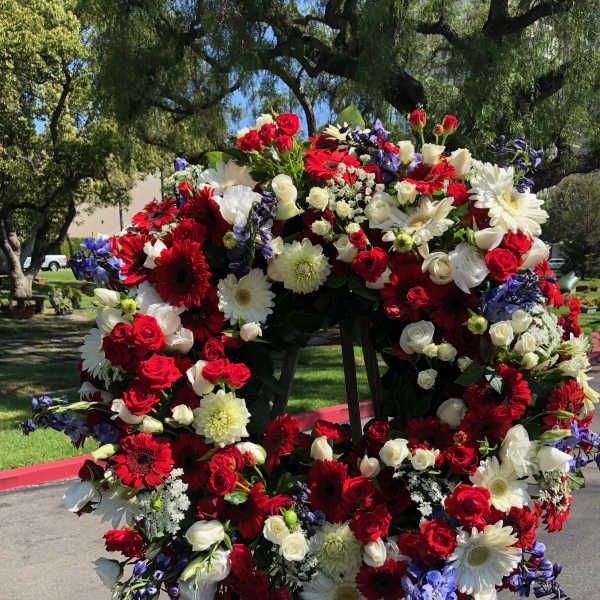 Large circular wreath of red, white, and purple flowers on an easel