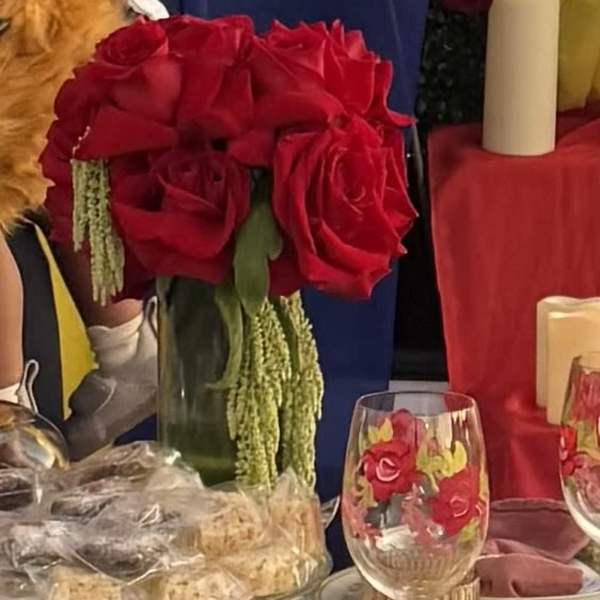 Red rose centerpiece in a glass vase on a decorated table