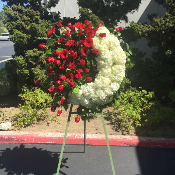 Red roses and white flowers arranged in a crescent on a stand