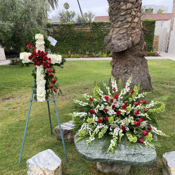 Two floral funeral tributes with red roses and white flowers outdoors