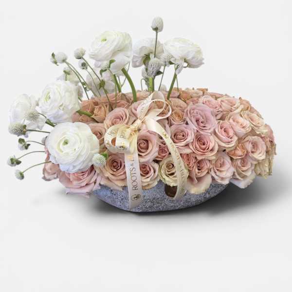 Blush and white rose arrangement in a low round container