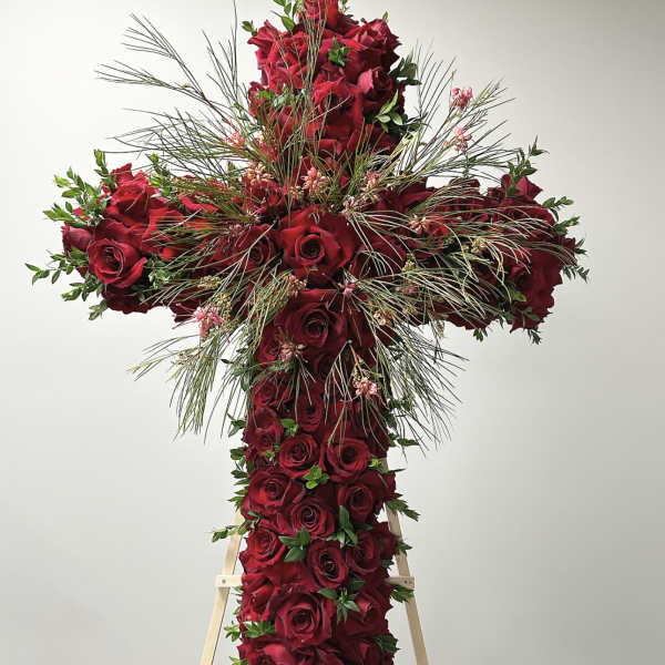 Cross-shaped arrangement of red roses with wispy greenery on a stand