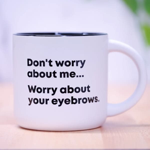White mug with black text reading "Don't worry about me... Worry about your eyebrows."