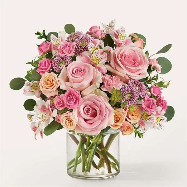 Pink and peach bouquet of roses, alstroemeria, and mums in a clear glass vase