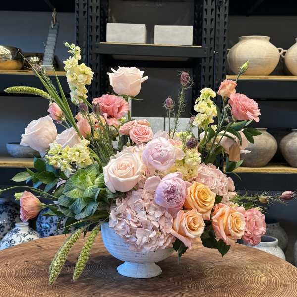 Pastel floral arrangement in a white pedestal vase