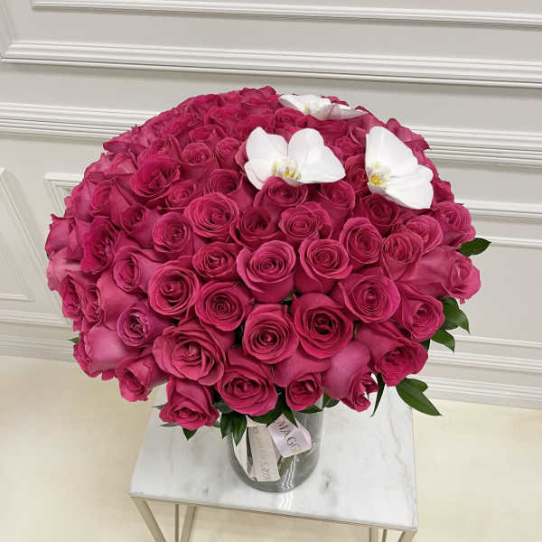 Large bouquet of hot pink roses with white orchids in a glass vase