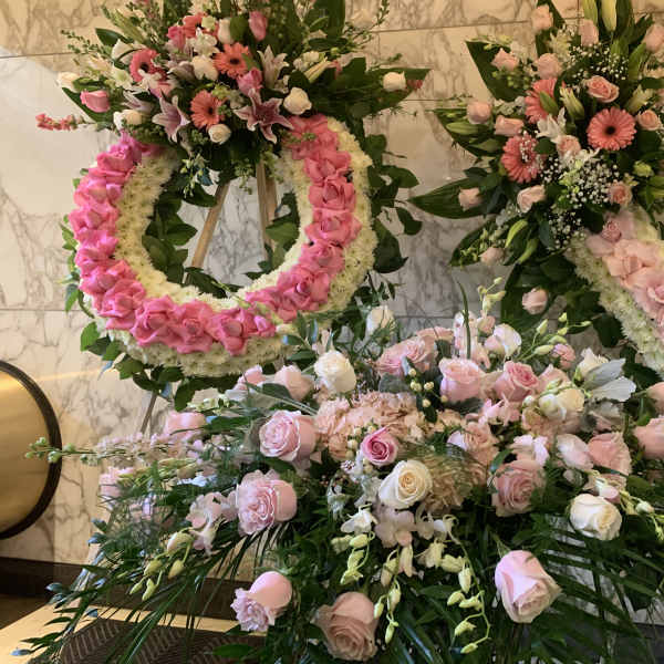 Pink and white floral wreaths and bouquets arranged on stands