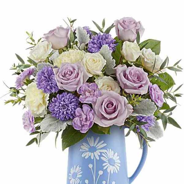 Lavender roses and purple flowers in a blue pitcher vase