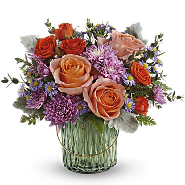 Bouquet of peach and orange roses with purple daisies in a glass vase