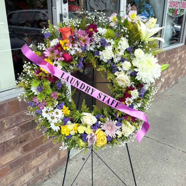 Large floral wreath on a stand with a pink ribbon reading "LAUNDRY STAFF"