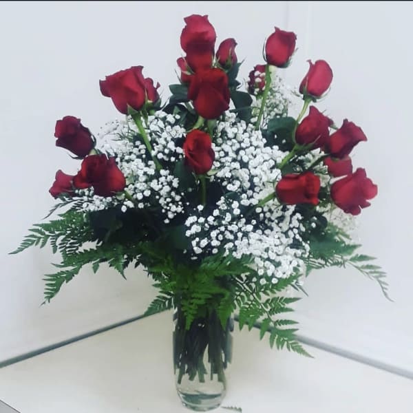 Bouquet of red roses and white baby's breath in a clear glass vase