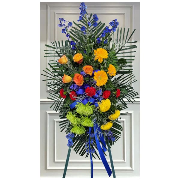 Tall standing floral spray with blue, yellow, red, and green flowers
