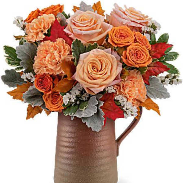 Orange and peach roses arranged in a brown pitcher vase