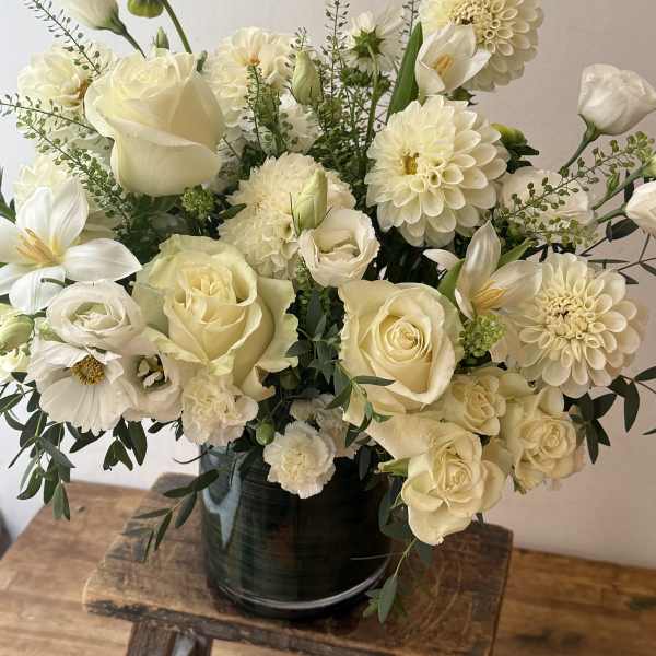 Creamy white bouquet of roses, dahlias, and calla lilies in a dark vase