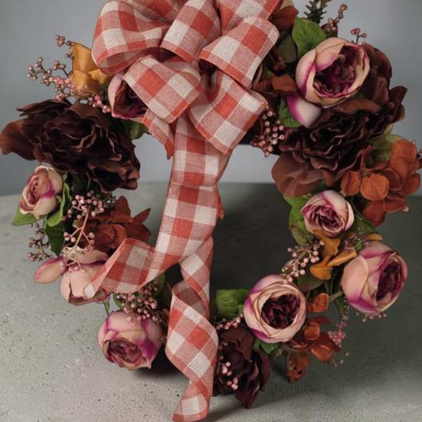 Floral wreath with pink and burgundy roses and a plaid ribbon bow