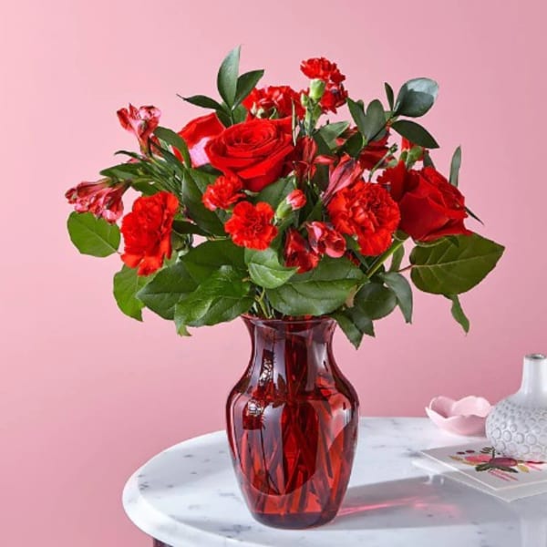 Red roses and carnations in a red glass vase