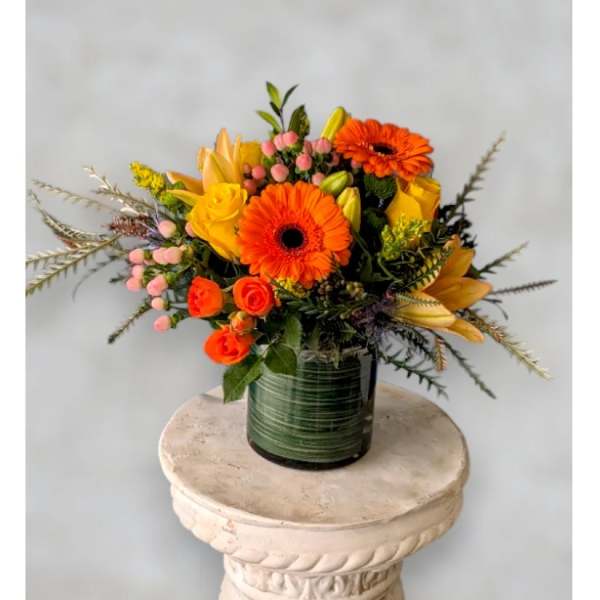 Orange and yellow mixed flower arrangement in a glass vase