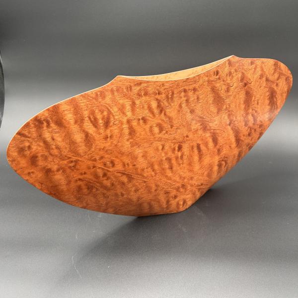 Curved wooden bowl with a glossy burl finish on a dark background
