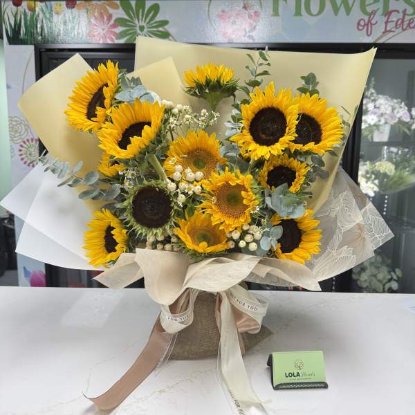 Bouquet of sunflowers wrapped in cream paper with a ribbon bow
