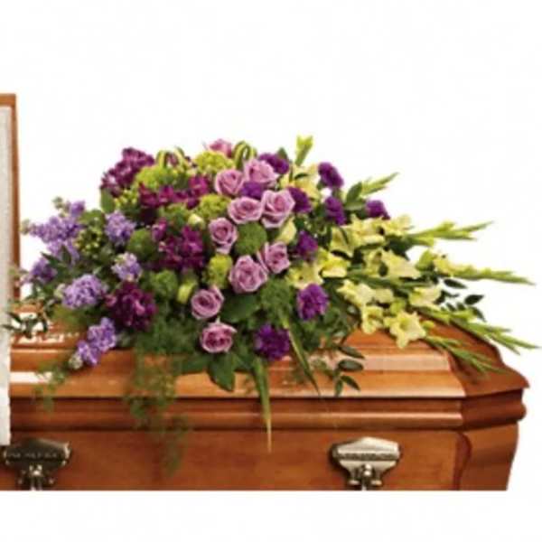 Purple and lavender floral spray on a wooden casket