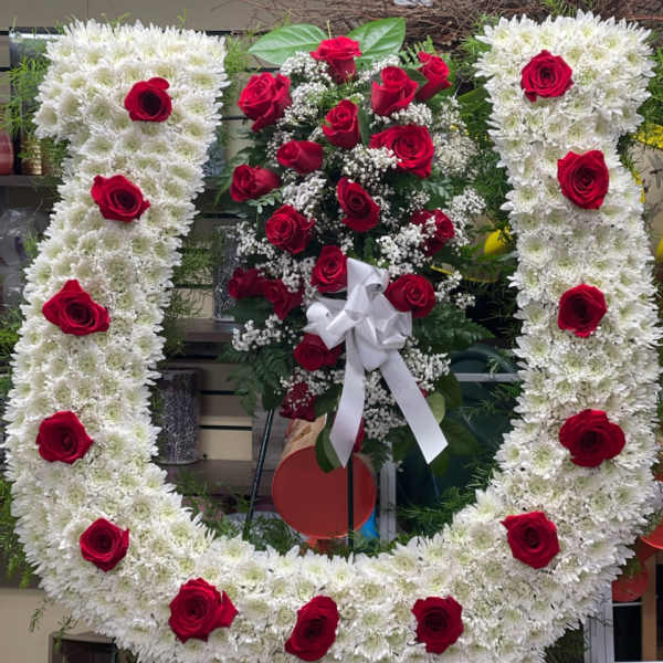 Large floral wreath of white chrysanthemums with red roses and a white bow