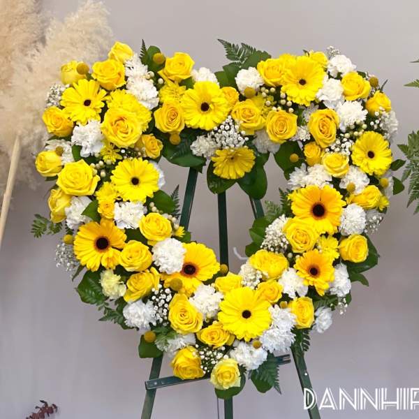 Yellow floral heart wreath on a stand with roses and daisies