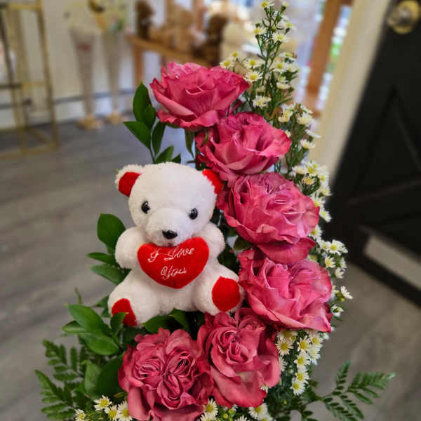 Pink roses with a teddy bear in a wooden container