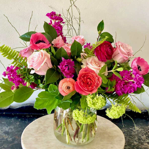 Mixed pink and red flowers arranged in a clear glass vase