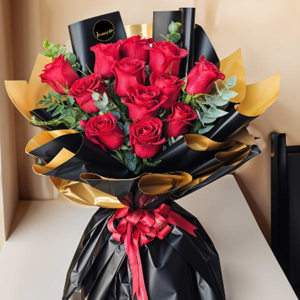 Bouquet of red roses wrapped in black and gold paper with a red ribbon