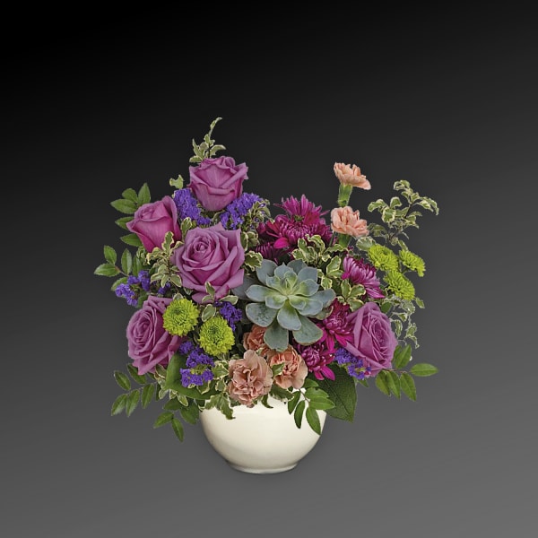 Purple roses and mixed flowers arranged in a white vase