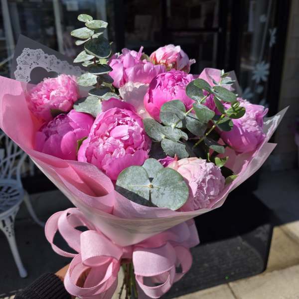 Pink peony bouquet wrapped in pink paper with a ribbon