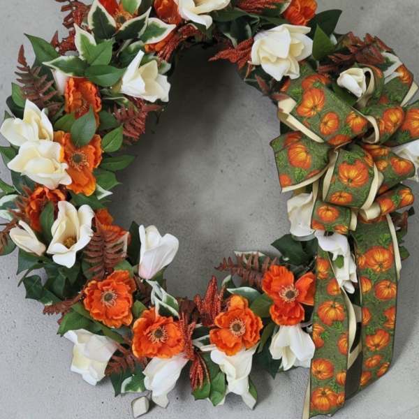 Autumn wreath with white and orange flowers and a pumpkin ribbon bow