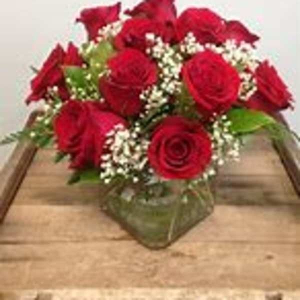 Red roses arranged in a low glass vase with baby's breath