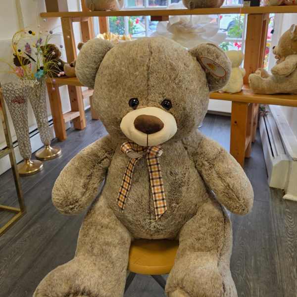 Large plush teddy bear with a plaid ribbon bow