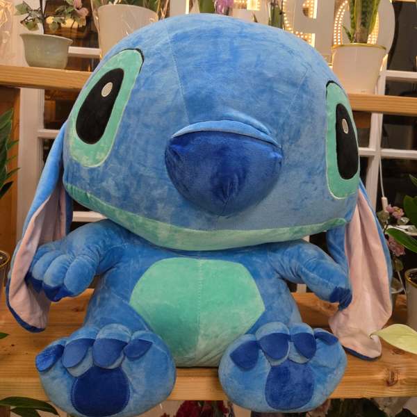 Large blue plush Stitch toy sitting in a flower shop display