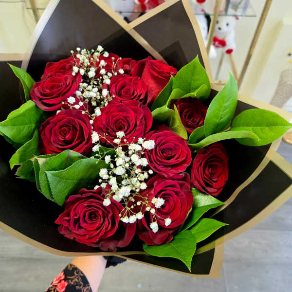 Bouquet of red roses with white baby's breath in black and gold wrap