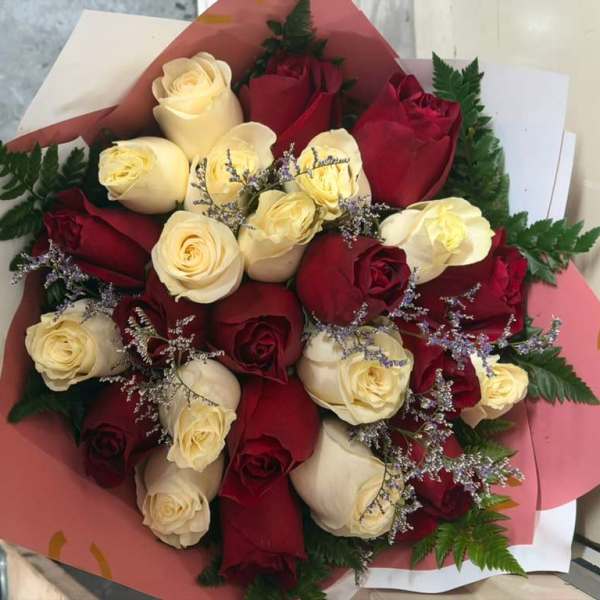 Bouquet of red and cream roses wrapped in pink paper